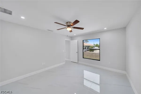 an empty room with window and ceiling fan