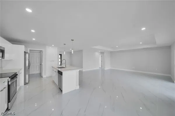a large white kitchen with stainless steel appliances a sink and cabinets
