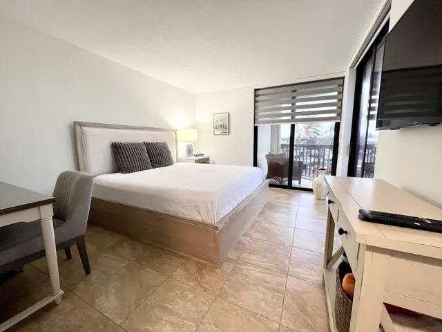 a bedroom with a bed and a flat tv screen on the dresser