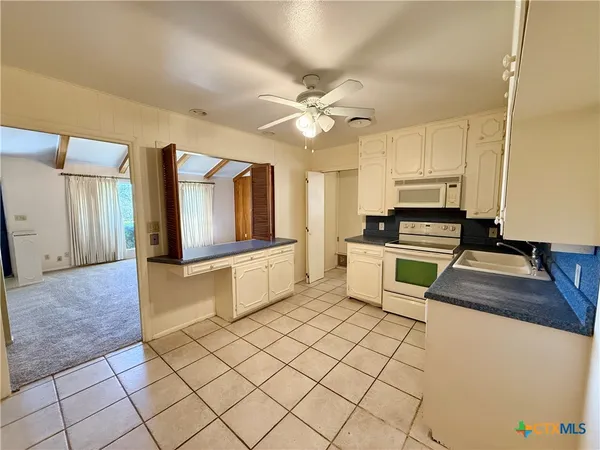 a kitchen with granite countertop a stove a sink and a refrigerator