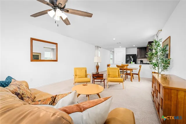 a living room with furniture and a dining table with wooden chairs