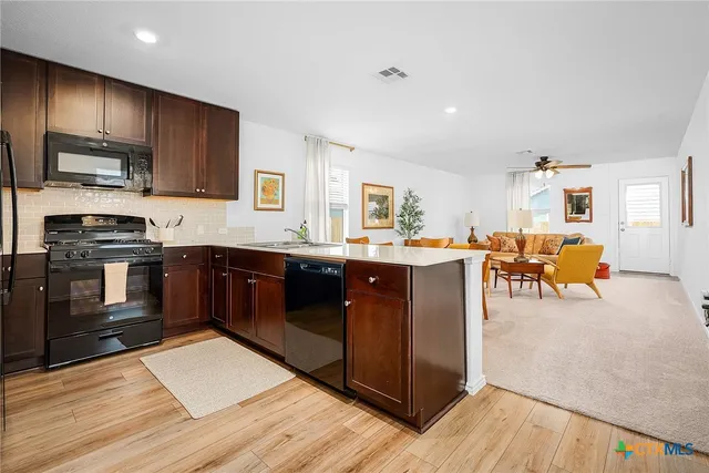 a kitchen with stainless steel appliances granite countertop wooden cabinets a sink dishwasher a stove and a refrigerator