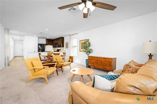a living room with furniture kitchen view and a large window