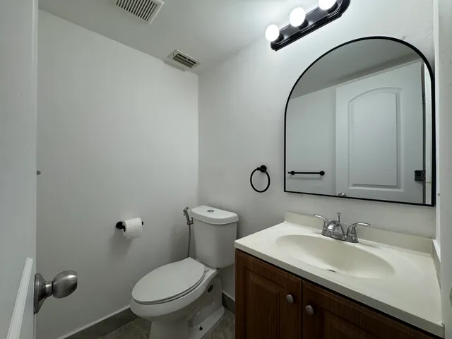 a bathroom with a granite countertop toilet sink and mirror