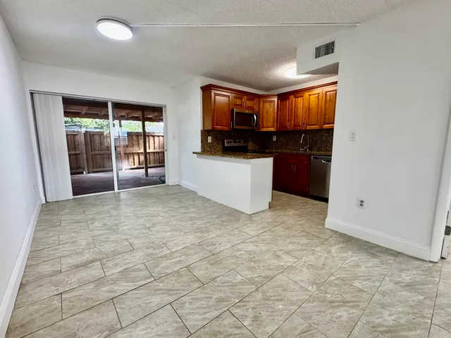 a living room with stainless steel appliances kitchen island granite countertop a refrigerator and a sink