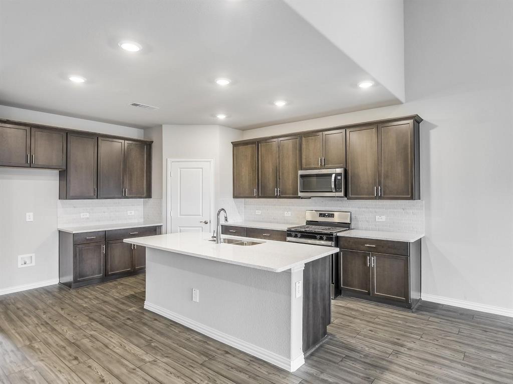2256 Bellatrix Drive Haslet, TX 76052 - Photo 7 of 24 a kitchen with stainless steel appliances granite countertop a stove top oven a sink dishwasher and a refrigerator with wooden floor
