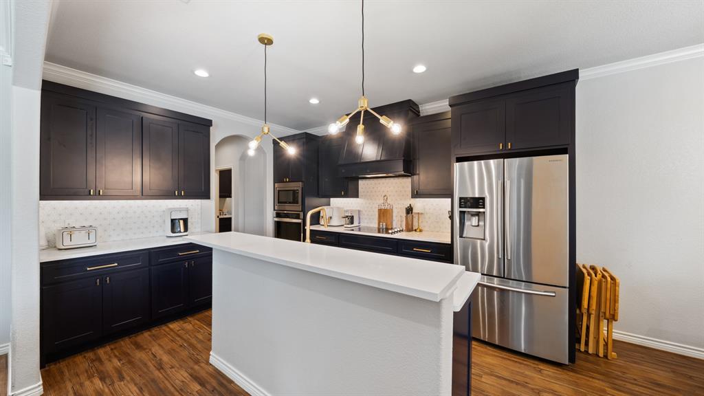 101 Lighthouse Lane Mabank, TX 75143 - Photo 10 of 40 Kitchen featuring stainless steel appliances, crown molding, hanging light fixtures, backsplash, and dark wood finished floors