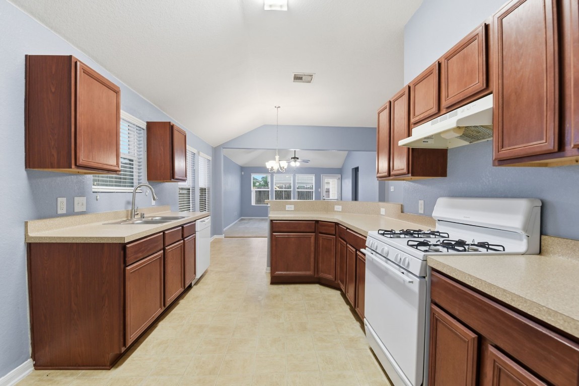 16763 North Blue Jay Drive Conroe, TX 77385 - Photo 7 of 26 a kitchen with stainless steel appliances granite countertop a stove top oven a sink dishwasher and a refrigerator with wooden cabinets