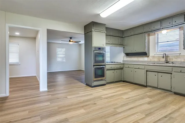 a kitchen with stainless steel appliances a sink cabinets and wooden floor