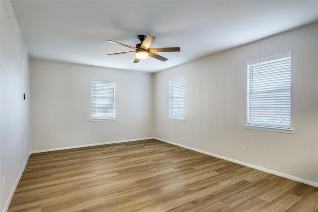 a view of empty room with wooden floor and fan