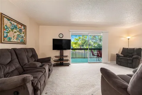 a living room with furniture floor to ceiling window and a flat screen tv