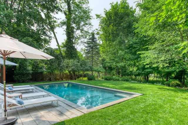 a view of a swimming pool with lawn chairs under an umbrella