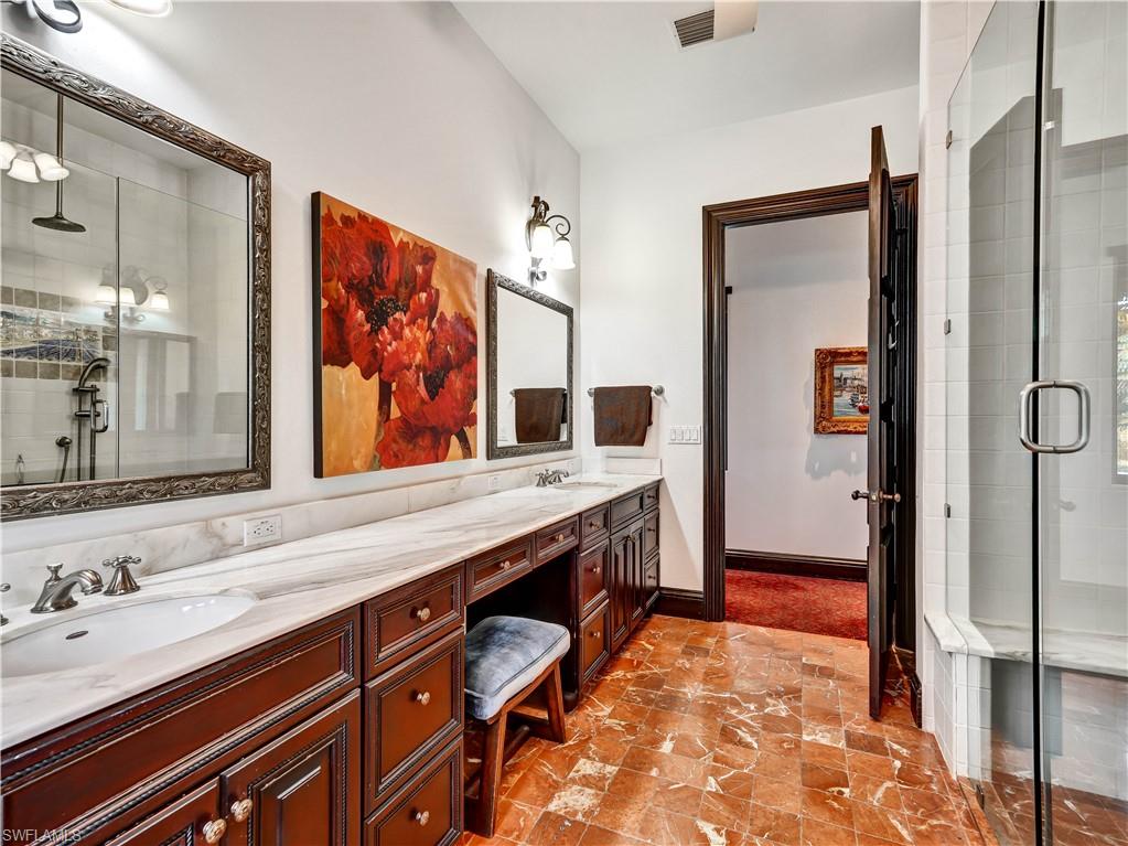 2535 Tarpon Road Naples, FL 34102 - Photo 27 of 50 Expansive vanity with rich wood cabinetry, dual undermount sinks, and a light-toned countertop
