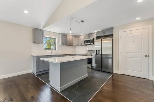 a large kitchen with stainless steel appliances a sink and a refrigerator