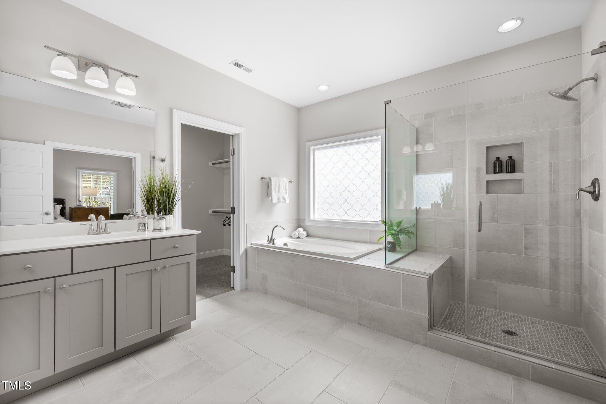 1013 Manchaca Loop Apex, NC 27539 - Photo 26 of 50 a spacious bathroom with a bathtub shower sink and mirror