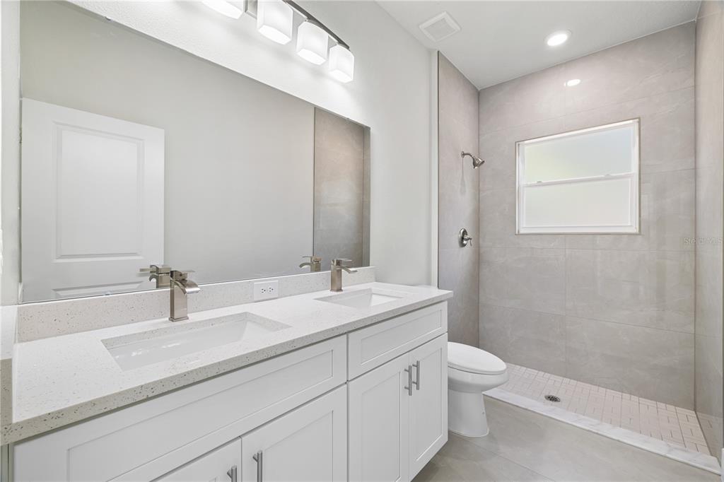16054 Southwest 29th Court Road Ocala, FL 34473 - Photo 16 of 27 a bathroom with a double vanity sink toilet mirror and shower