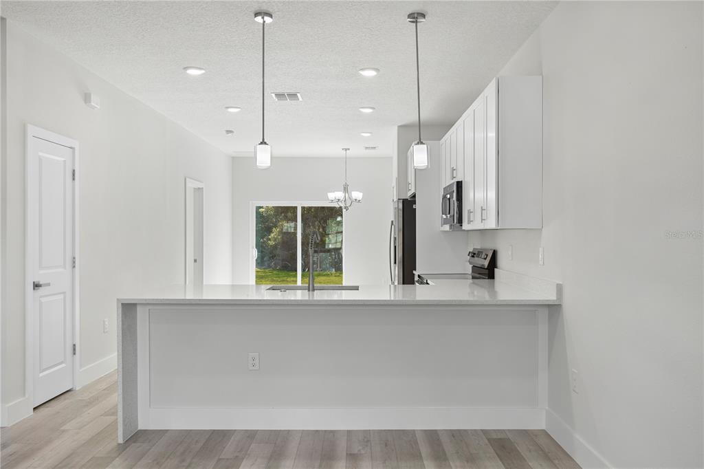 16054 Southwest 29th Court Road Ocala, FL 34473 - Photo 5 of 27 a large white kitchen with kitchen island a stove a sink and a window