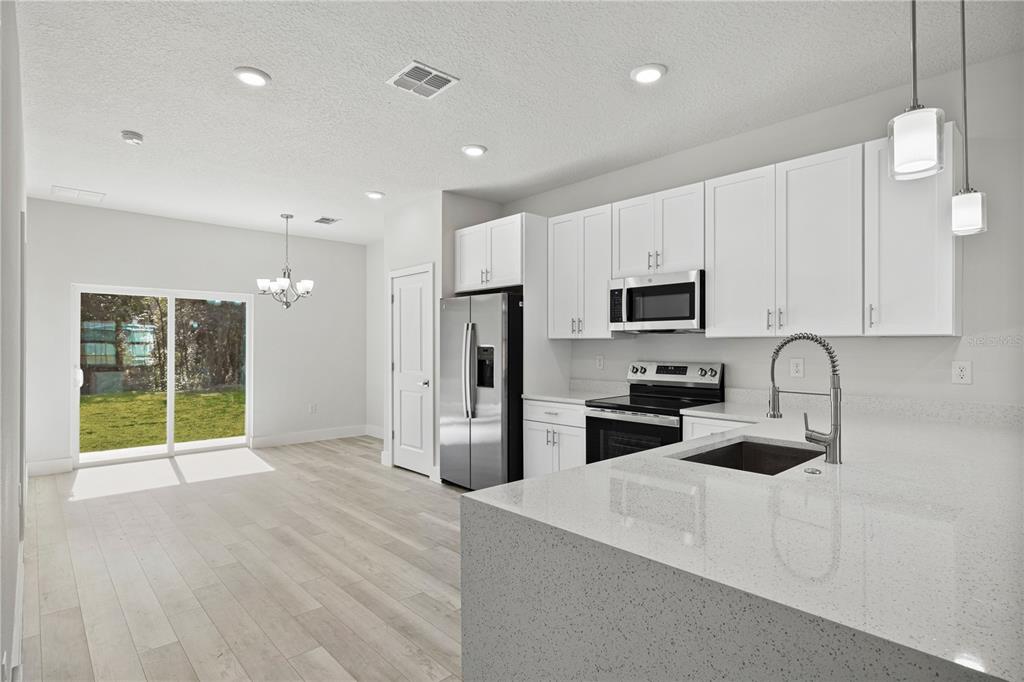 16054 Southwest 29th Court Road Ocala, FL 34473 - Photo 6 of 27 a kitchen with stainless steel appliances granite countertop a stove a sink and a refrigerator with white cabinets