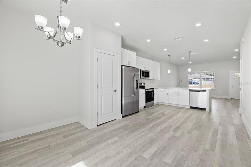 16054 Southwest 29th Court Road Ocala, FL 34473 - Photo 10 of 27 a view of a kitchen with stainless steel appliances granite countertop a refrigerator oven a sink dishwasher and white cabinets with wooden floor