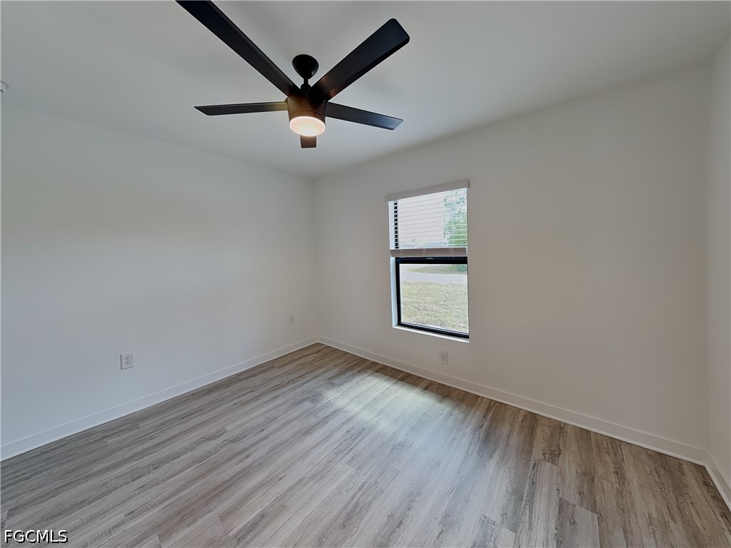 3201 23rd Street Southwest Lehigh Acres, FL 33976 - Photo 9 of 15 an empty room with wooden floor ceiling fan and windows