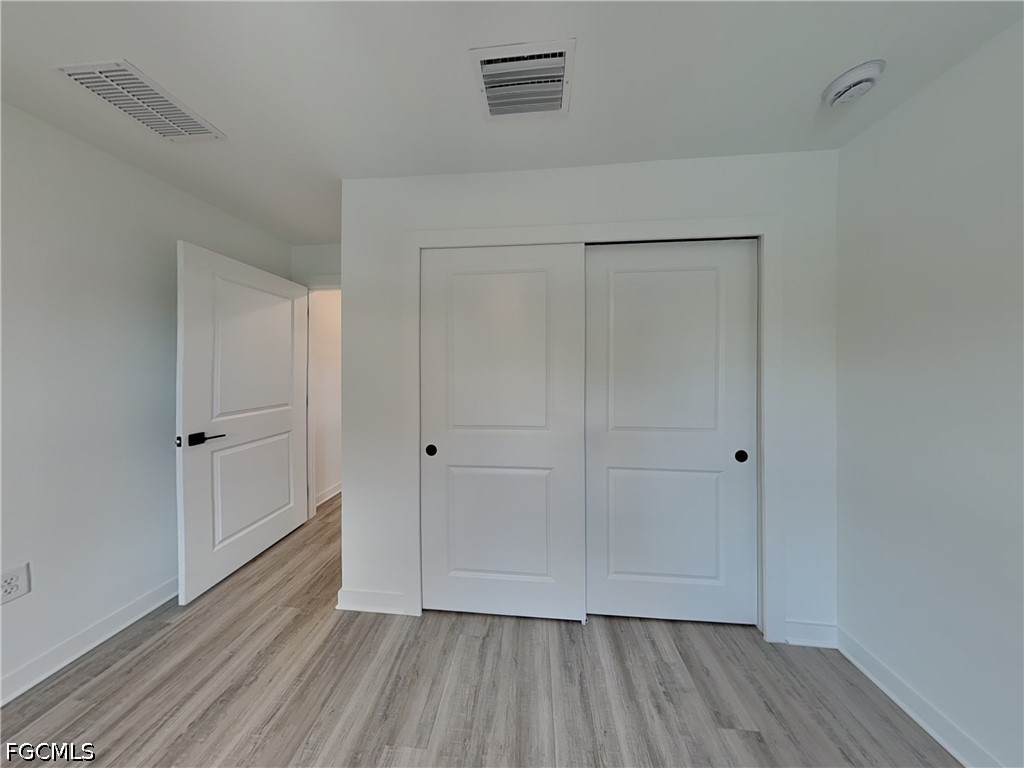 3201 23rd Street Southwest Lehigh Acres, FL 33976 - Photo 10 of 15 a view of an empty room with closet and wooden floor