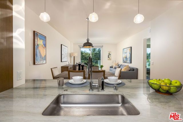 a dining table with a kitchen island stainless steel appliances furniture a chandelier a rug kitchen view and a chandelier