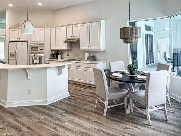 a kitchen with a table chairs refrigerator and microwave