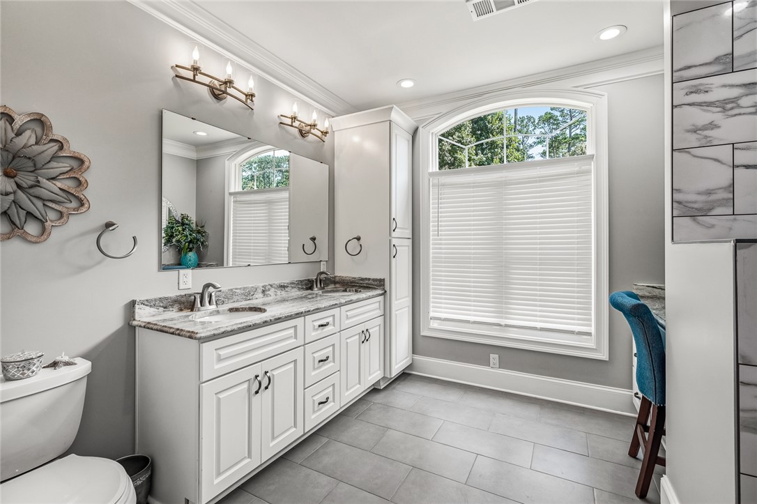 206 James Hare Road Anderson, SC 29626 - Photo 15 of 50 A pristine primary bathroom featuring dual sinks, ample vanity storage, and a large arched window for natural illumination.