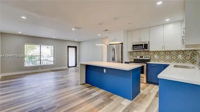 a kitchen with wooden floors a sink stainless steel appliances and windows