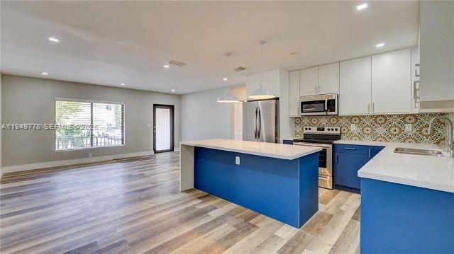1050 Southwest 11th Street, Unit 1052 Miami, FL 33129 - Photo 2 of 10 a kitchen with wooden floors a sink stainless steel appliances and windows