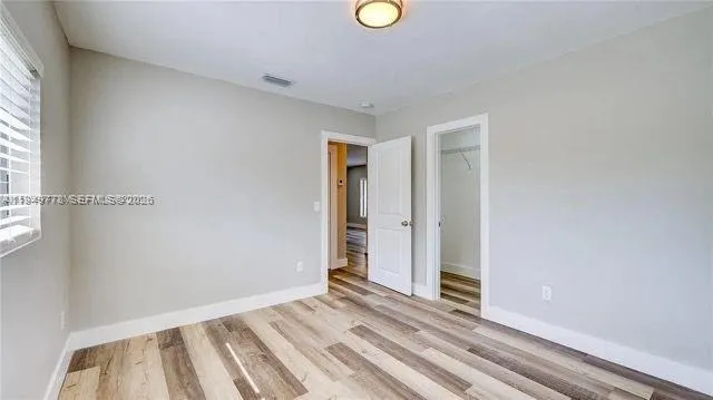 a view of an empty room with wooden floor and a window