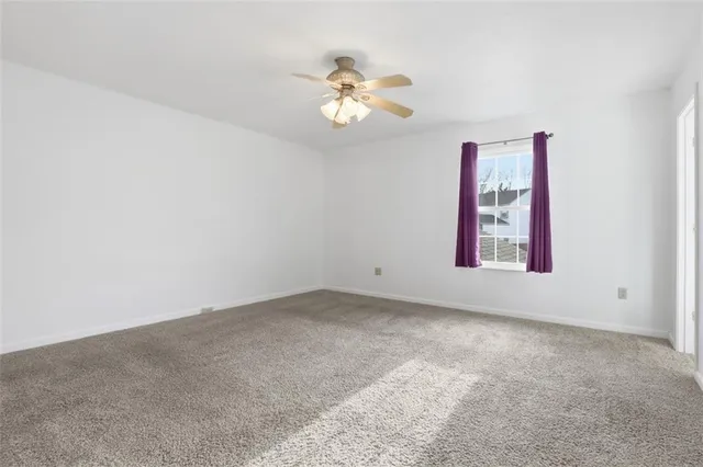 an empty room with windows and chandelier fan