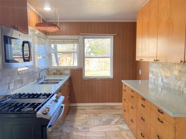 a kitchen with granite countertop cabinets stainless steel appliances a sink and a window