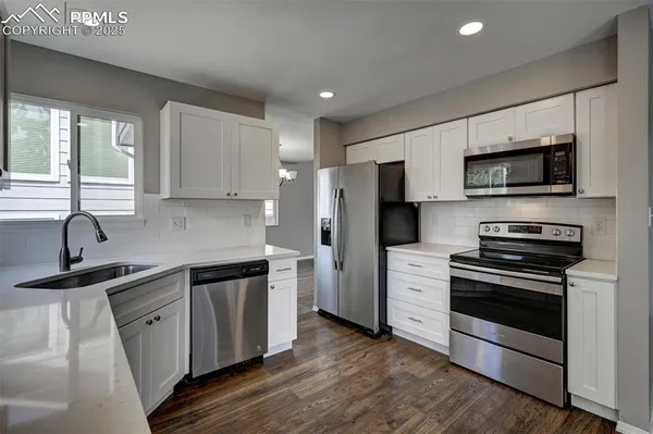 a kitchen with stainless steel appliances a sink dishwasher a refrigerator and a stove top oven with wooden floor