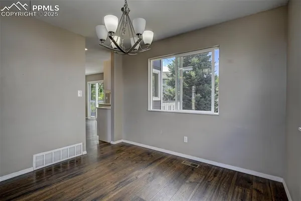 a view of a room with wooden floor chandelier and windows