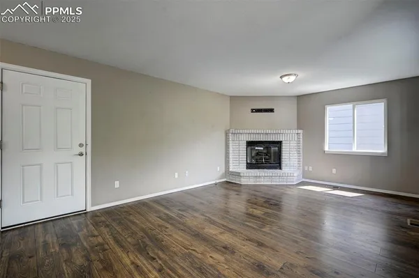 an empty room with wooden floor and fireplace
