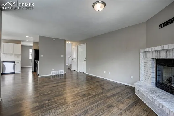 a view of a livingroom with wooden floor and a fireplace