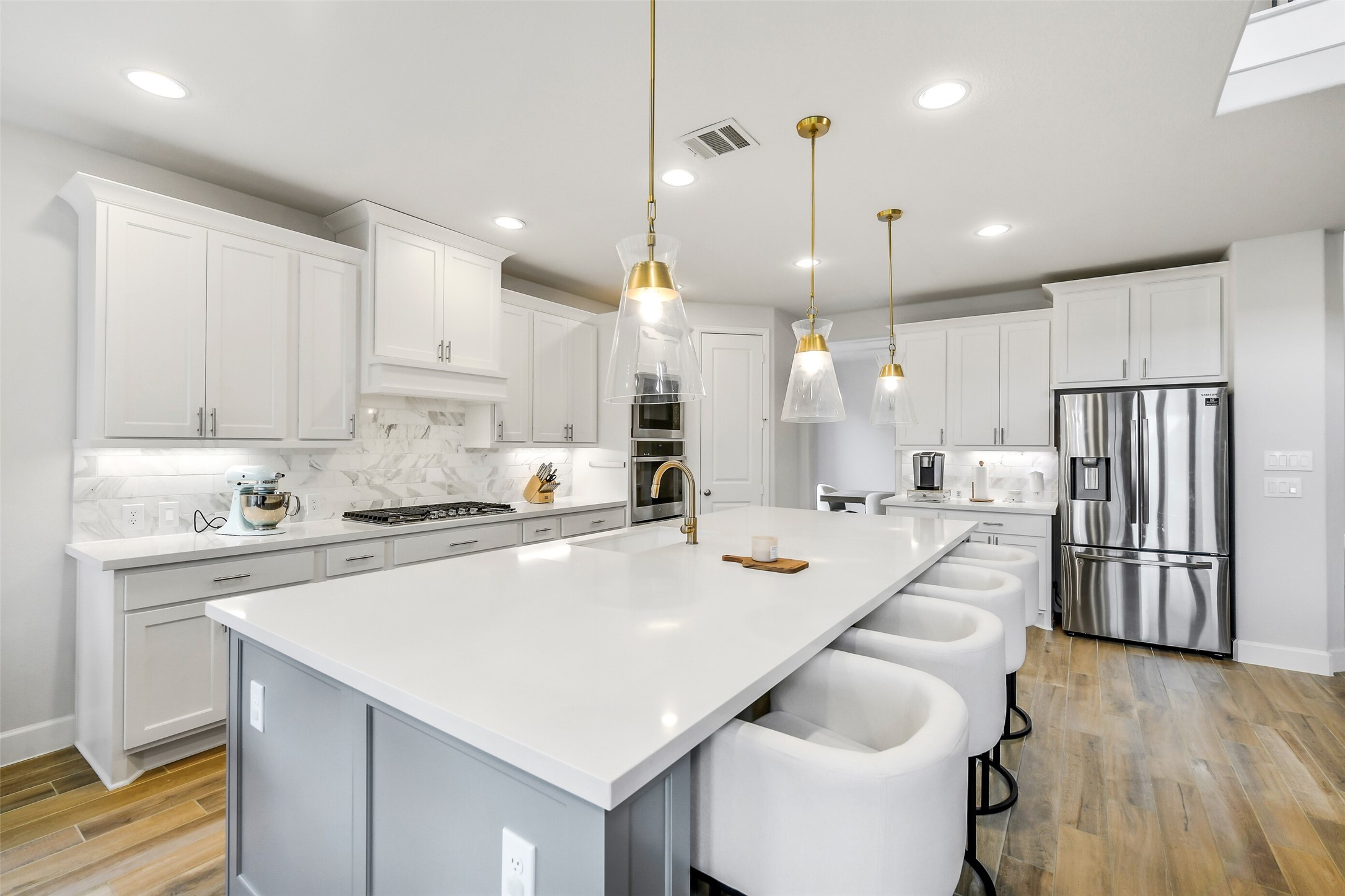 21222 Rabbitbrush Court Cypress, TX 77433 - Photo 9 of 36 a kitchen with kitchen island a stove a refrigerator a sink and white cabinets with wooden floor