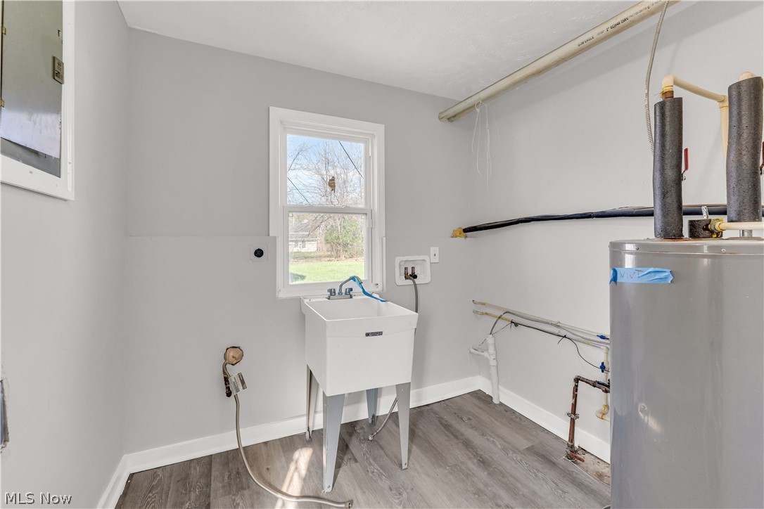 2521 Greenvale Road Cleveland, OH 44121 - Photo 21 of 23 Utility room featuring a laundry basin, large window, water heater, and wood-finish flooring