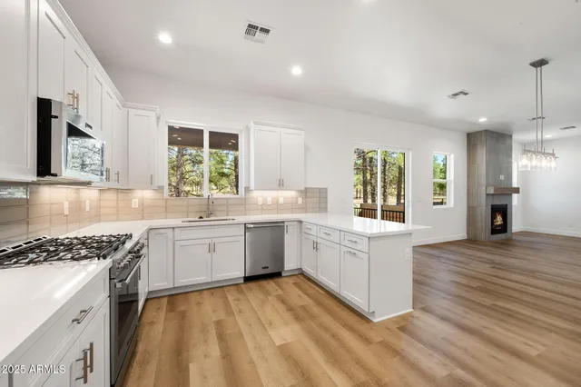 a kitchen with granite countertop a stove a sink dishwasher and white cabinets with wooden floor