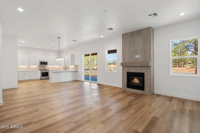 a view of an empty room and a kitchen with wooden floor and a fireplace
