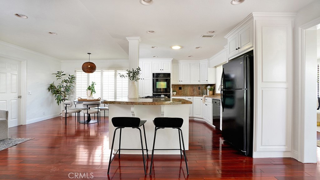 25312 Pizarro Road Lake Forest, CA 92630 - Photo 21 of 36 a kitchen with stainless steel appliances granite countertop a refrigerator a stove a dining table and chairs with wooden floor
