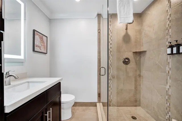 a bathroom with a shower sink vanity mirror and toilet