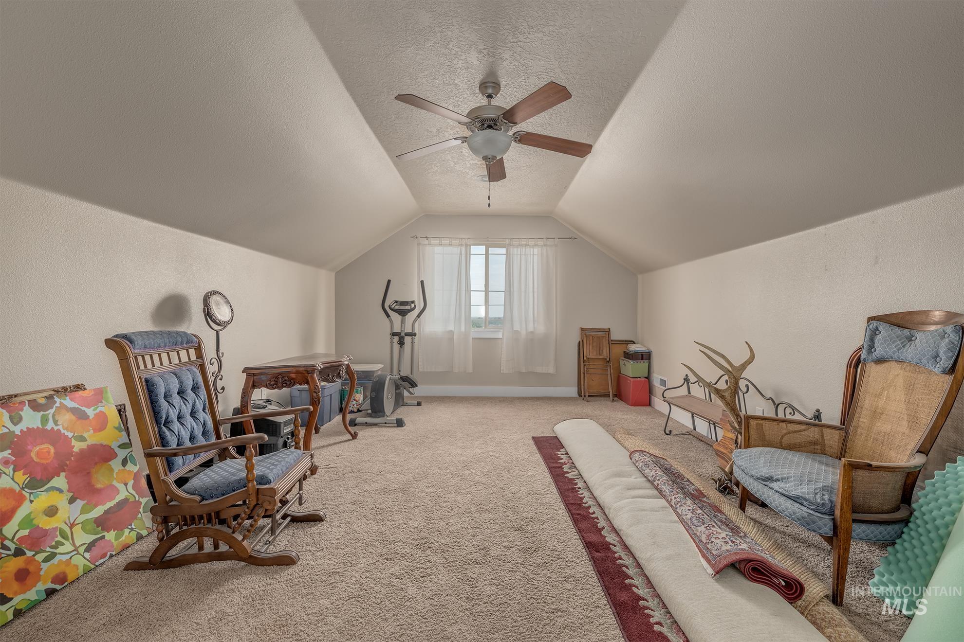 420 West Indianhead Road Weiser, ID 83672 - Photo 28 of 40 Expansive bonus room featuring vaulted ceilings with a ceiling fan, neutral carpet flooring, and a window with natural light
