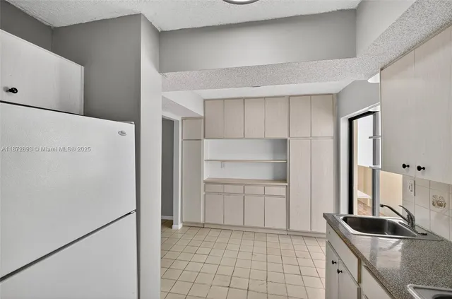 a kitchen with white cabinets and refrigerator