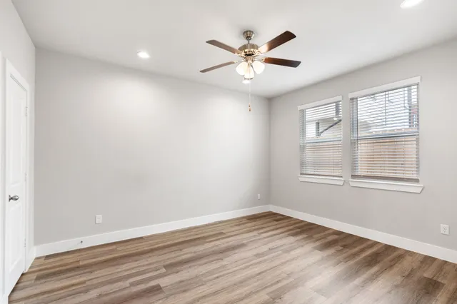 an empty room with wooden floor chandelier fan and closet area