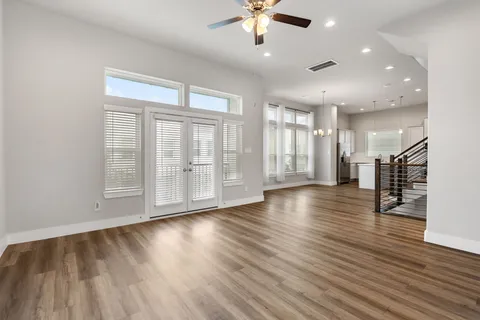 an empty room with wooden floor and ceiling fan