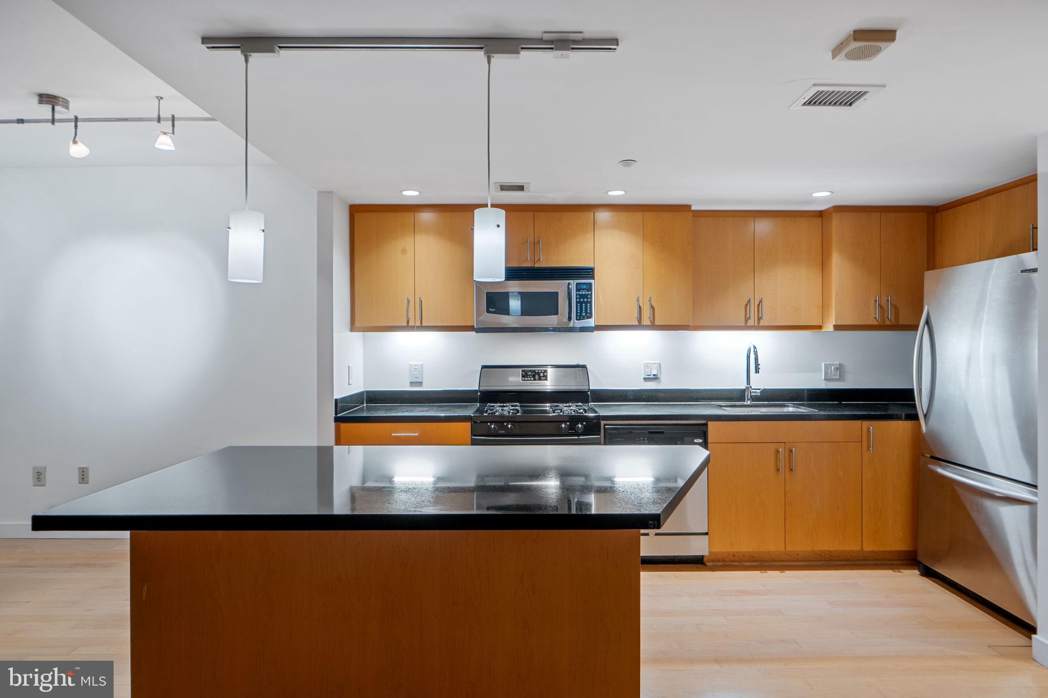 912 F Street Northwest, Unit 508 Washington, DC 20004 - Photo 12 of 40 a kitchen with stainless steel appliances granite countertop a sink a stove and a refrigerator