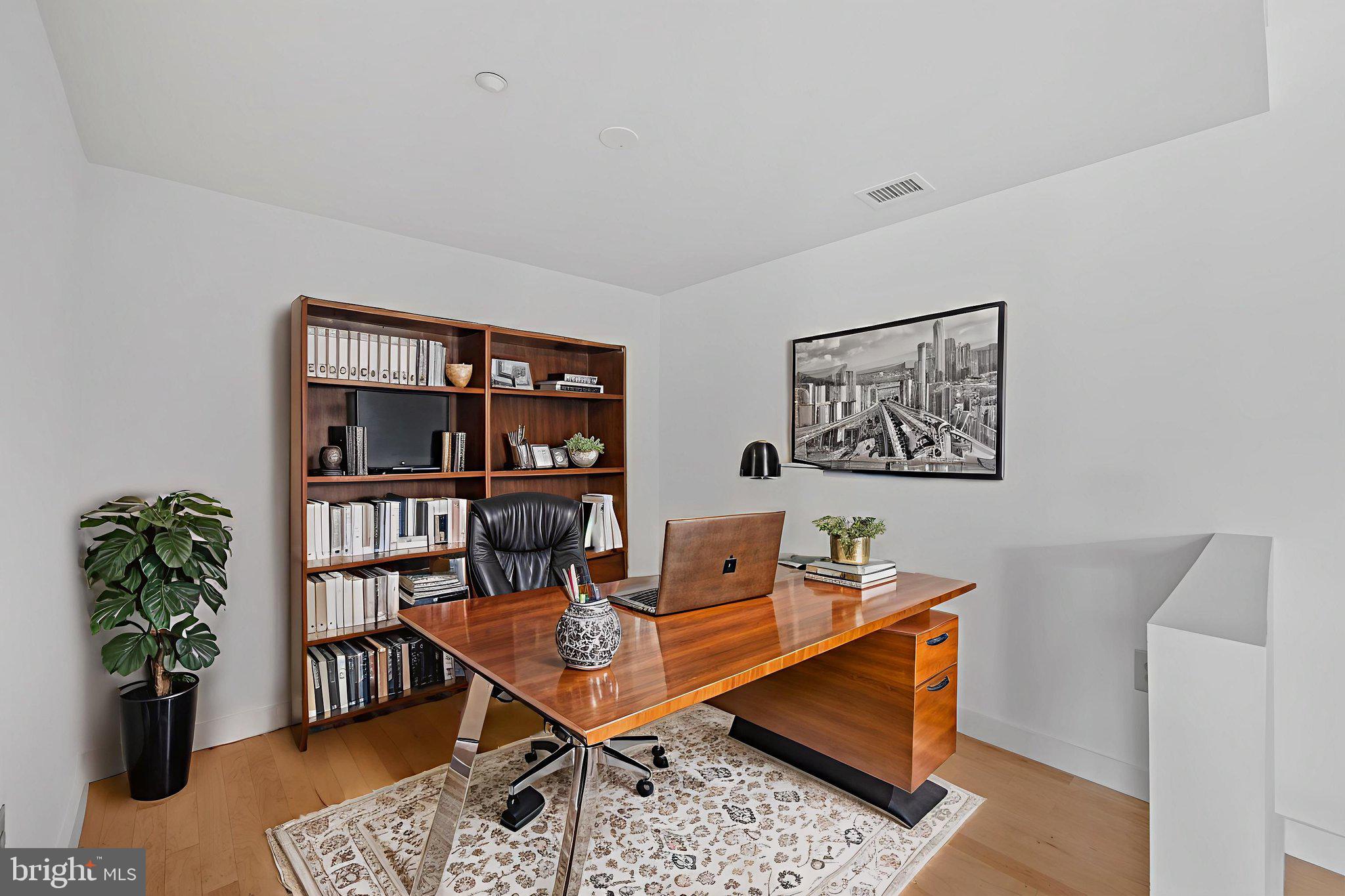 912 F Street Northwest, Unit 508 Washington, DC 20004 - Photo 25 of 40 a living room with furniture a bookshelf and a potted plant