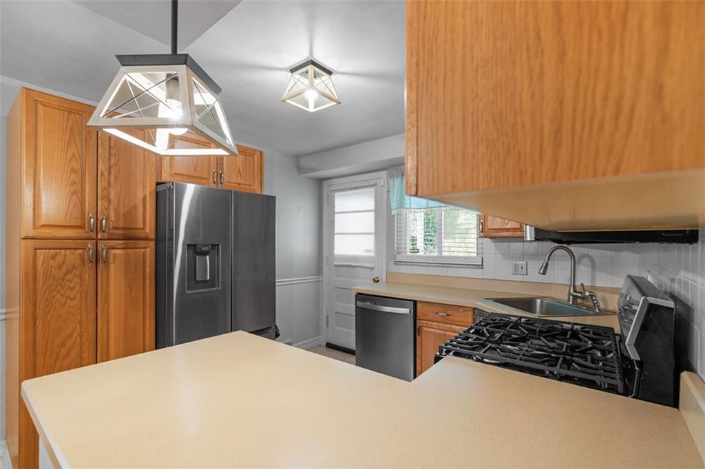 1538 Rutherford Avenue Pittsburgh, PA 15216 - Photo 25 of 43 a kitchen with stainless steel appliances granite countertop a refrigerator a sink dishwasher a stove and a dining table with wooden floor